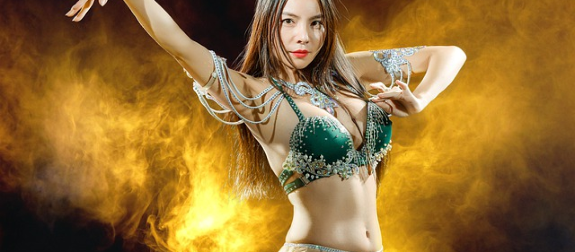 An image that captures the vibrant essence of belly dancing: a confident, graceful woman adorned in a shimmering costume, her fluid movements reflecting empowerment and timeless beauty