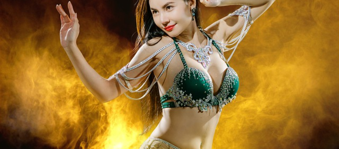 An image showcasing a belly dancer's hands delicately selecting vibrant, jewel-toned fabrics, a table adorned with musical instruments, and a notebook filled with meticulously written choreography notes