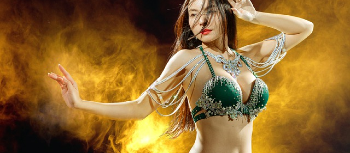 An image capturing a mesmerizing belly dancer gracefully twirling a sheer, iridescent veil, its delicate fabric flowing through the air like a magical stream of colors, embodying the essence of the Ultimate Guide To Belly Dancing Veil Dances